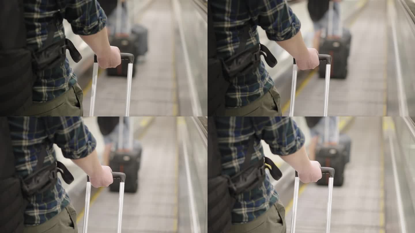 一名亚洲乘客带着带轮子的旅行袋走在移动走道上穿过机场航站楼