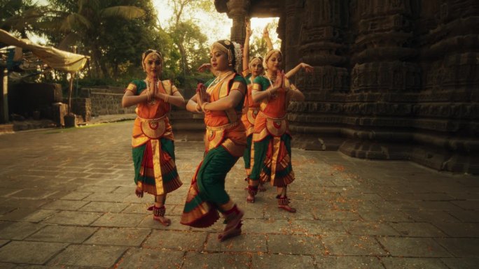 五名妇女在古庙附近表演民间舞蹈的慢动作肖像。印度妇女穿着色彩鲜艳的传统服装，美丽地表演多手舞