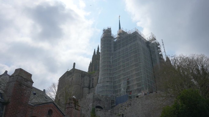 阴天，圣米歇尔山修道院在脚手架下重建和翻新的低角度近景。