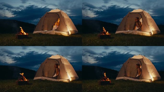 年轻女子拉开帐篷的拉链，在篝火旁眺望
