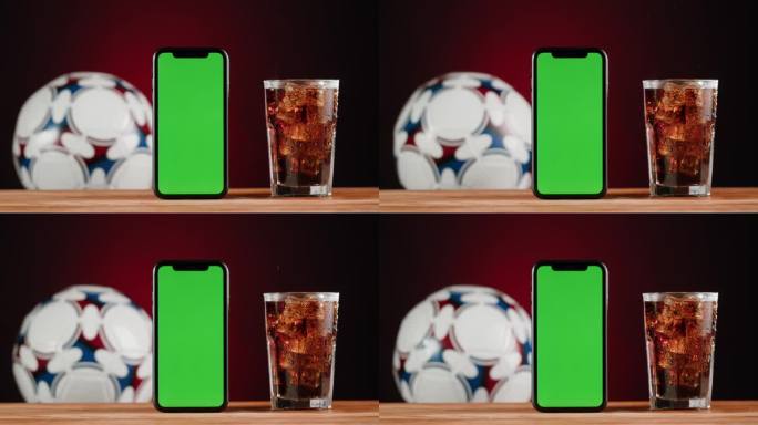 玻璃杯里的冷柠檬水特写。看足球时喝的饮料。可乐与冰微距拍摄纹理。清爽鸡尾酒。绿色色度键屏的智能手机。