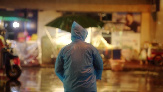 一个年轻人正在过马路，而在市中心的晚上下着大雨。