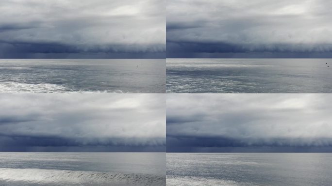 广阔的航拍画面，海浪滚滚涌向海岸，黑暗，戏剧性的风暴云在银色的海洋上移动