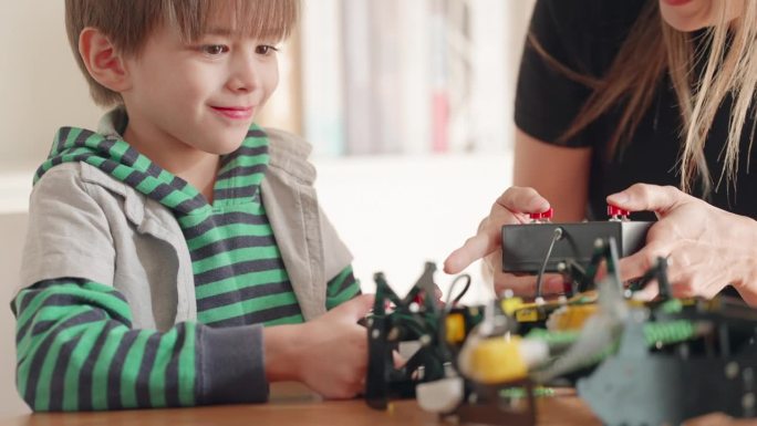 小学生在教室里。男孩玩机器人玩具玩得很开心，在教室里练习组装机器人，老师给予建议和照顾。提高工程技能