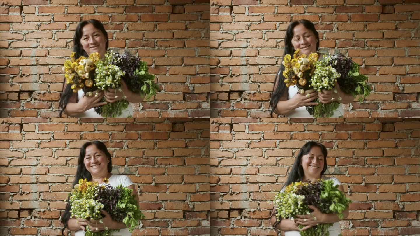 4 k的视频。实时视频。一位年轻女子拿着一束鲜花和草药，在中性的背景下愉快地摆姿势。复制空间。实时视