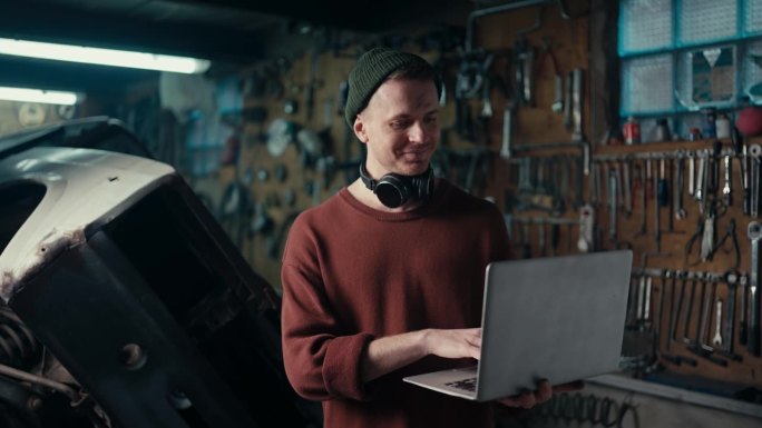 掌握生产力:熟练的专业人员在棕色毛衣和绿色的帽子在笔记本电脑上工作
