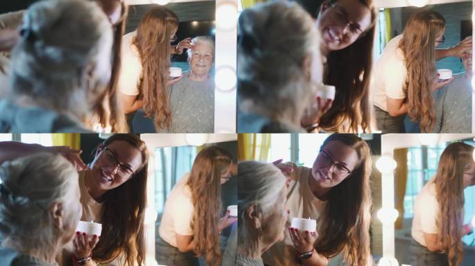 成年的女儿在家里对着镜子给老母亲的脸上涂抗皱霜