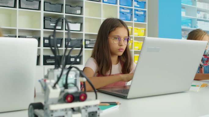 书呆子白人女孩在笔记本电脑上为机器人编写程序