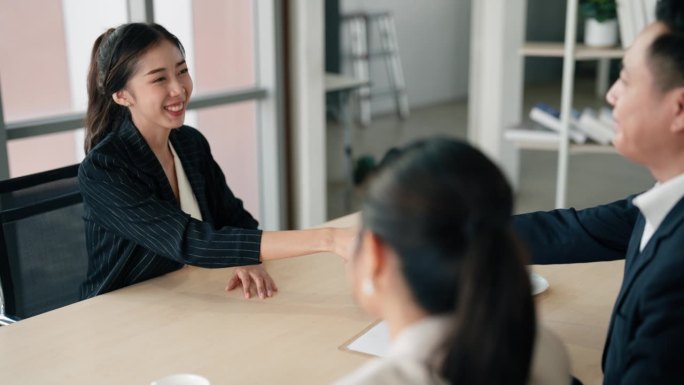 一位亚洲女性候选人在两名商人同意为她提供一份工作后，正在注册申请。