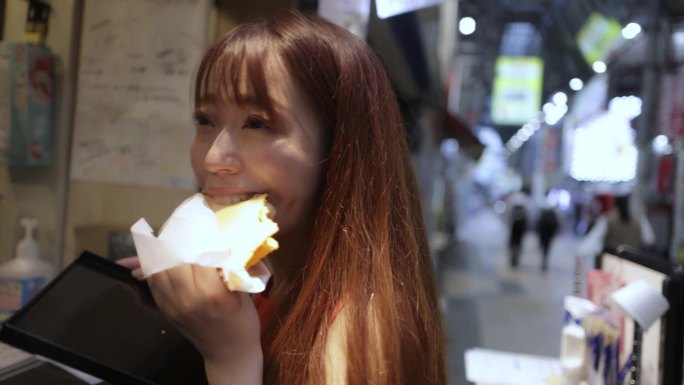 在城市里吃“Tako Sen”街头小吃的妇女