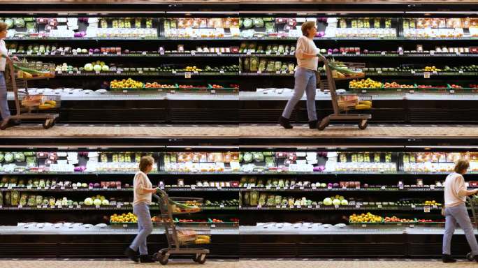 一个成熟的女人推着购物车走过超市的冷藏农产品区