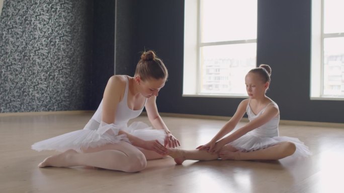 女教练在芭蕾舞课上伸展女孩的脚趾