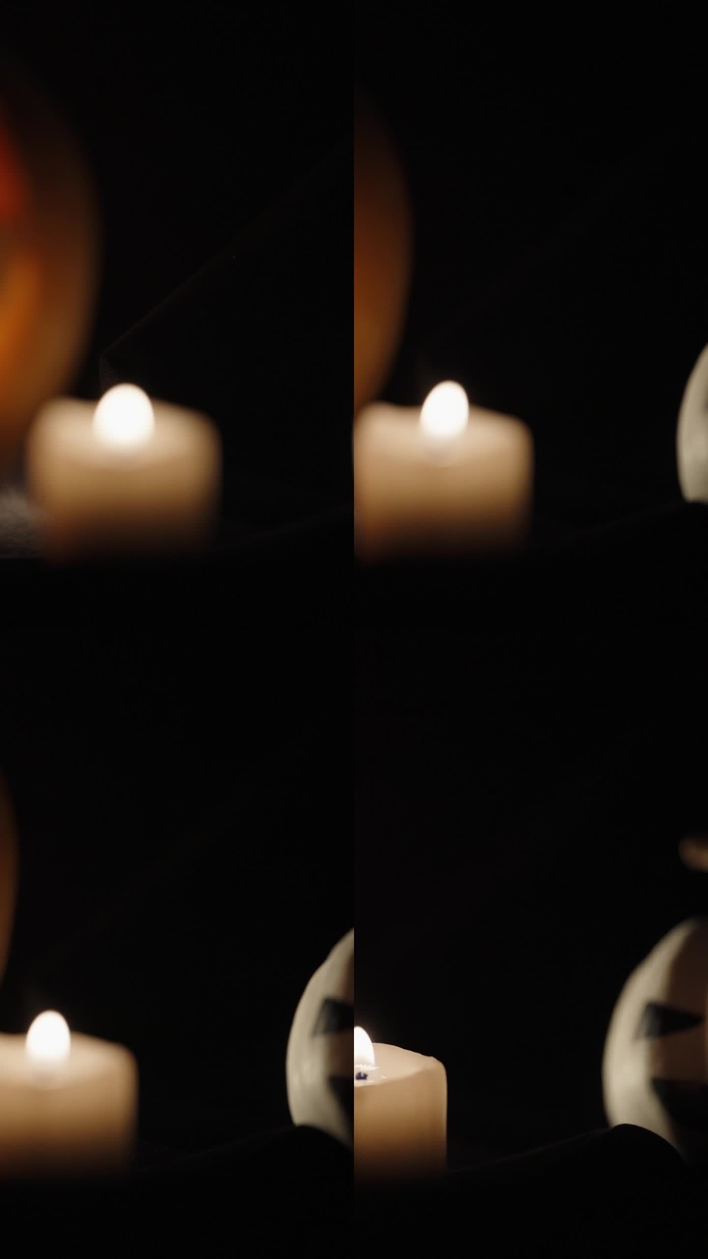垂直视频。两个万圣节南瓜，一个是白色的，上面插着蜡烛。照相机慢慢聚焦在他们身上。