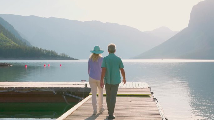 一对老年夫妇沿着木制湖码头散步