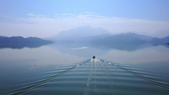 游艇行驶在静静的湖面，青山如黛，水天一色