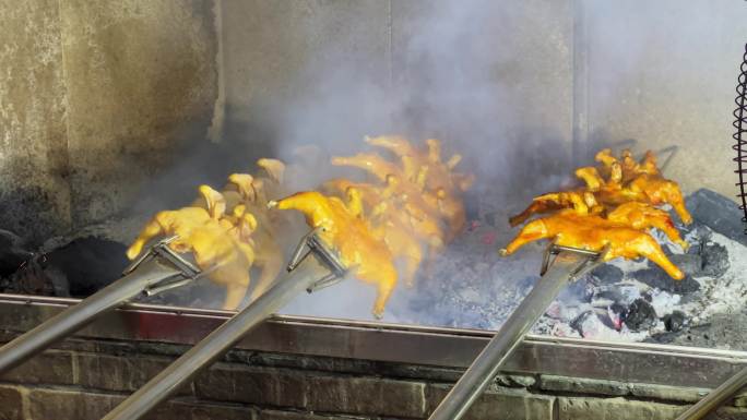 烧烤店的厨师使用炭火来烧烤整鸡，炭火烤鸡