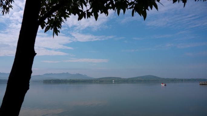 青山绿水蓝天白云下平静的湖面游船驶过