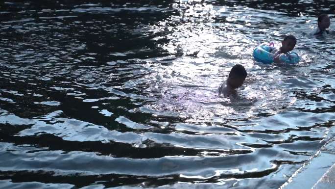 夕阳余晖里在河里戏水玩耍的孩子们