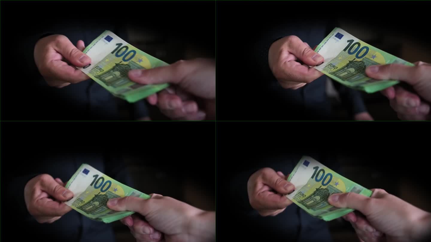 人们在黑暗的房间里试着分钱，一个人的手用力地拉着一叠100欧元的钞票，