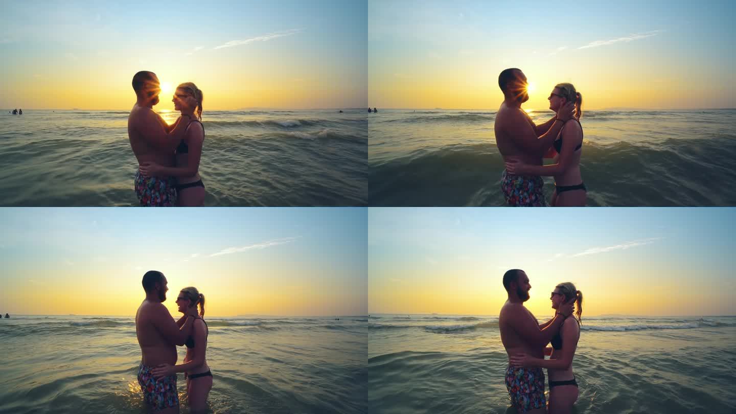 夏天旅行、度假时，一对相爱的情侣在海滩上一起看日落。拥抱的夫妇的剪影享受日落，日出的海洋在热带目的地