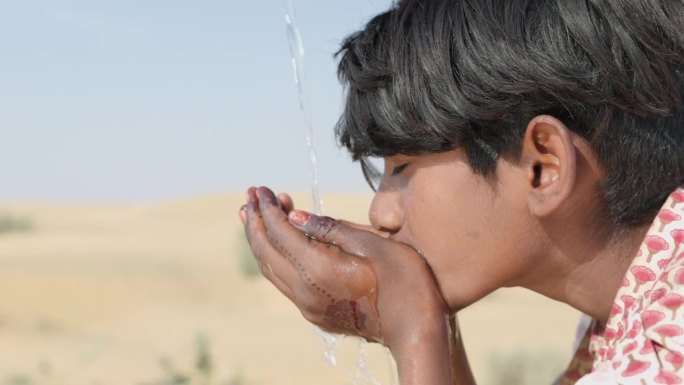 印度拉贾斯坦邦的沙漠村庄，一个印度小男孩在喝淡水
