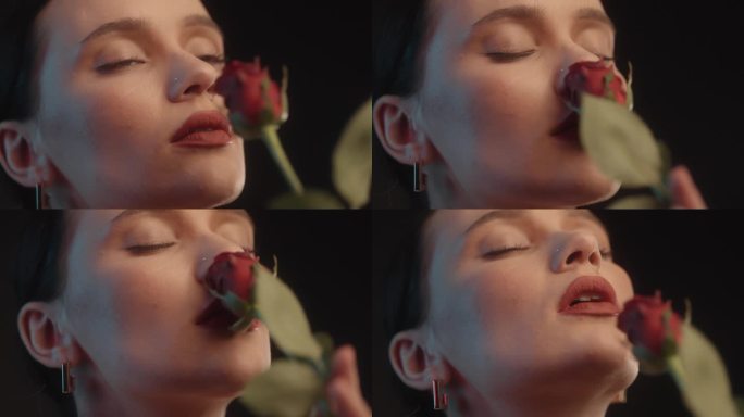 性感的女人用红色的口红黑色的背景工作室拍摄的姿势闻着一朵红玫瑰和调情的镜头