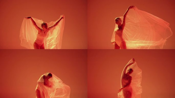 明度。柔弱的年轻女子，芭蕾舞演员在霓虹灯下用透明的布料在橙色的工作室背景下跳舞