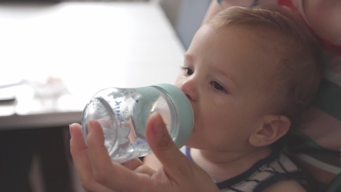 口渴的小男孩从奶瓶里喝水