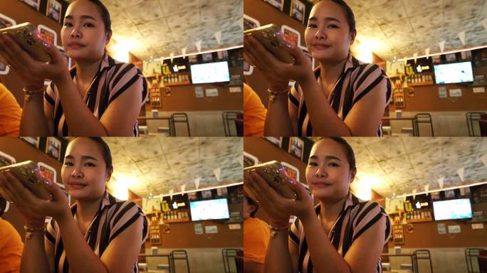一个亚洲女人在社交场合和朋友一起吃饭时看着镜头。