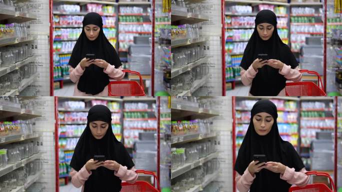 在一家超市的化妆品部，一位身穿粉色衬衫、头戴黑色头巾、提着红色购物篮的女士正在看智能手机。一位女士在