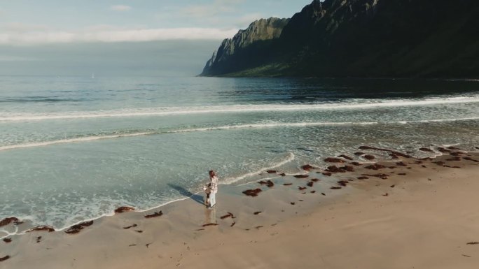 美丽的全景，十几岁的女孩在厄斯峡湾海滩上与大白色狗玩耍