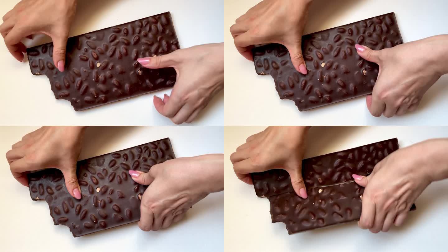 一名女子双手掰碎白色背景的黑巧克力棒。俯视图坚果零食视频。高品质4k画面