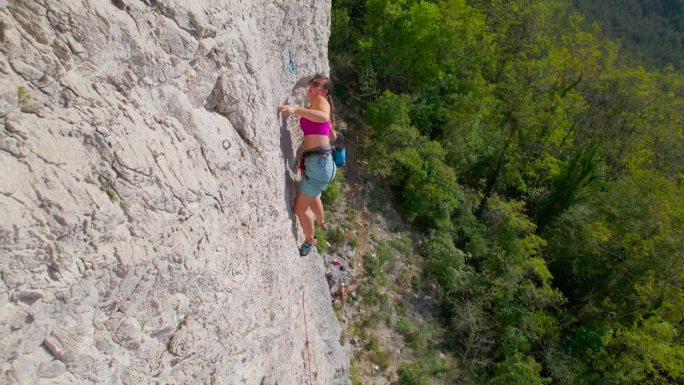 特写:运动女子在攀爬岩壁的同时，在快划中夹紧保护绳
