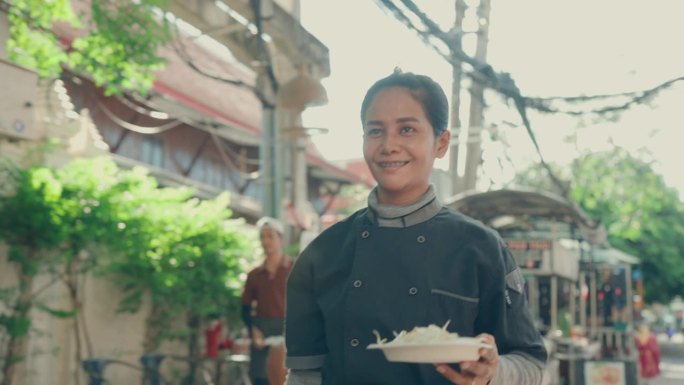 泰国饮食文化:女厨师在市场准备传统泰式炒粉。