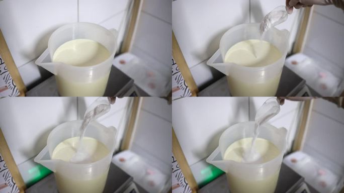 食品厂的工人将糖粉从勺子倒入混合桶中，加入冷霜，准备制作冰淇淋。
