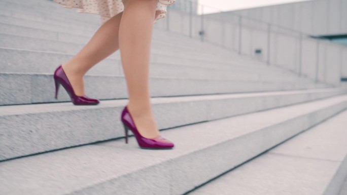 一个不知名的女人穿着裙子和紫色细高跟鞋走下城市的楼梯