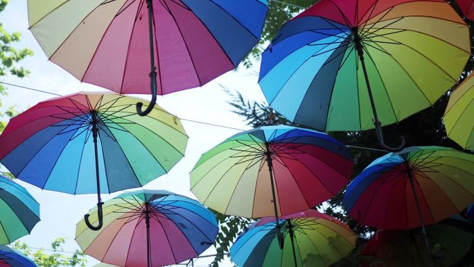 天空背景上的彩虹伞。许多五颜六色的雨伞。