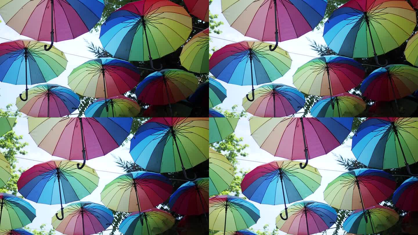 天空背景上的彩虹伞。许多五颜六色的雨伞。