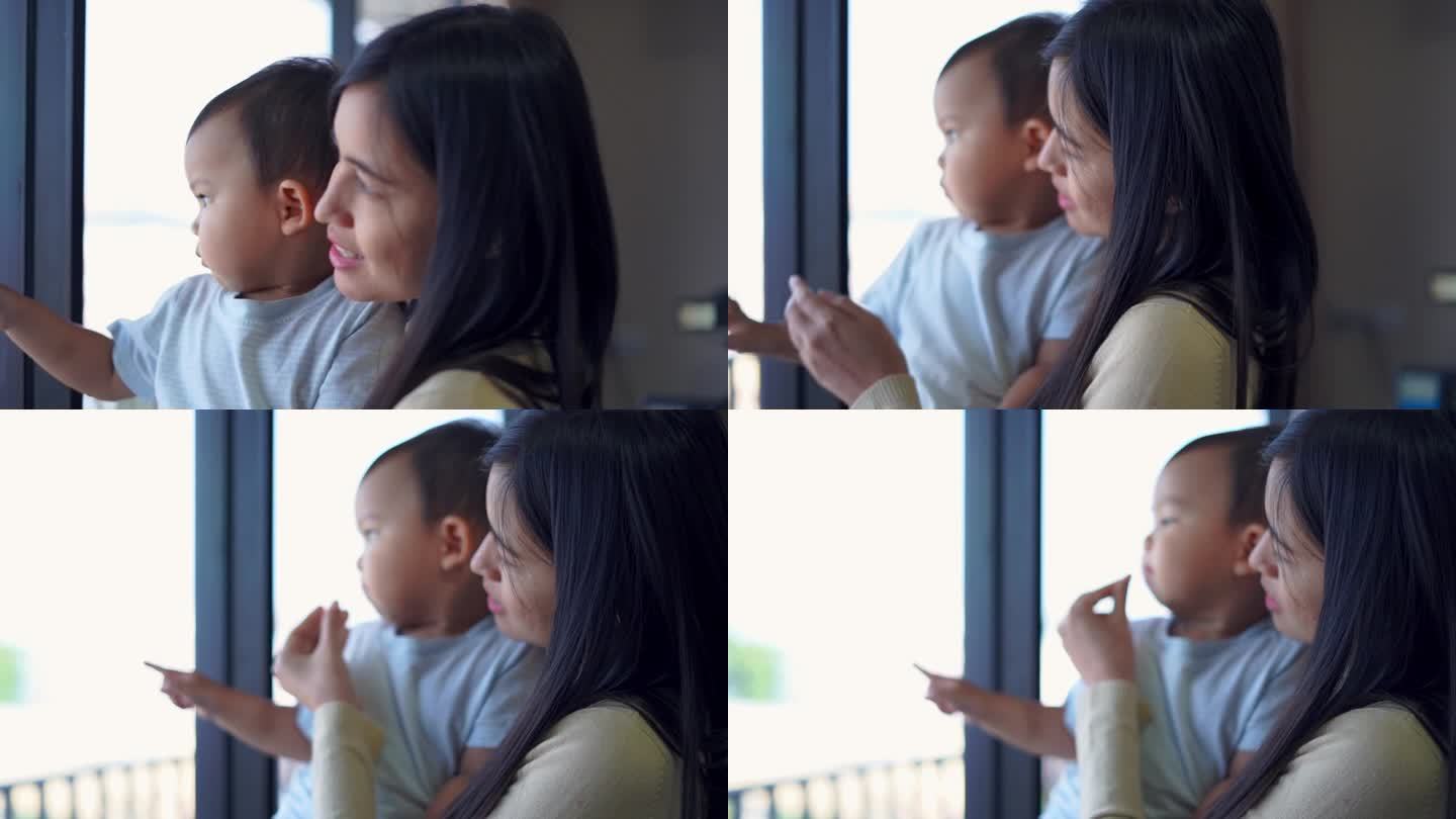年轻的母亲抱着小男孩，望着窗外。