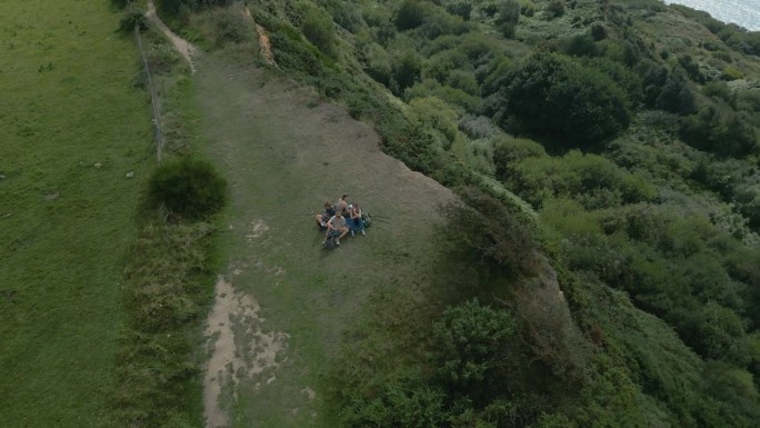 无人机航拍的一家人在英国多塞特郡侏罗纪海岸的海边悬崖上徒步旅行的画面