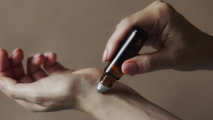 一位女士在她的手腕上涂抹天然滚轴芳香油。一位女士在她的手腕上涂抹天然滚轴芳香油。