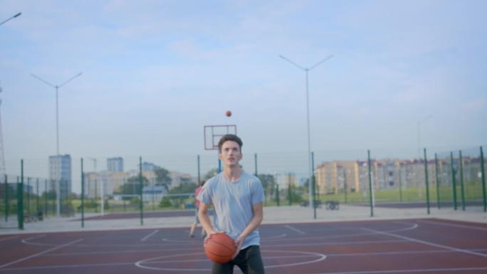 一个人练习把篮球扔进篮筐，空旷场地，摄像机跟踪