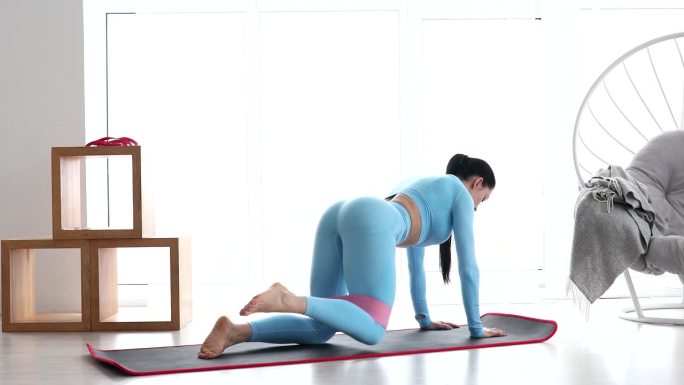 健身妇女在家用阻力带做提腿锻炼臀肌。运动女孩锻炼身体
