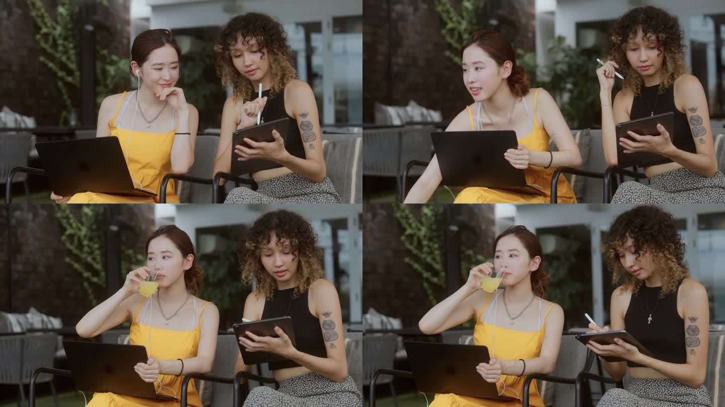 迷人的亚洲职业女性坐在河边的咖啡馆里，一边摆弄着数码平板电脑，一边和同事聊天。