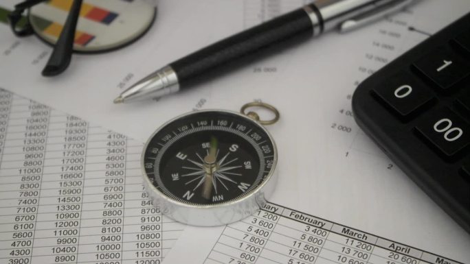 用笔、眼镜和计算器在财务报告上旋转指南针。