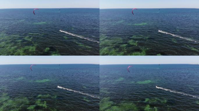 鸟瞰图年轻的白人女运动员骑着风筝在大海上冲浪。水上运动