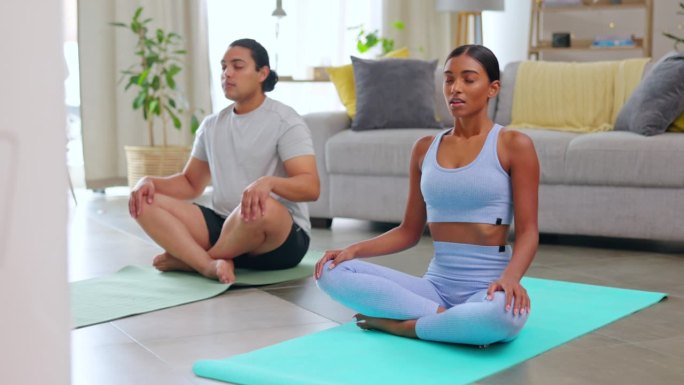 夫妻俩，在客厅练瑜伽，一起呼吸，在家里练禅，一起健身。锻炼，冥想和跨种族的人正念，脉轮和治疗在公寓锻
