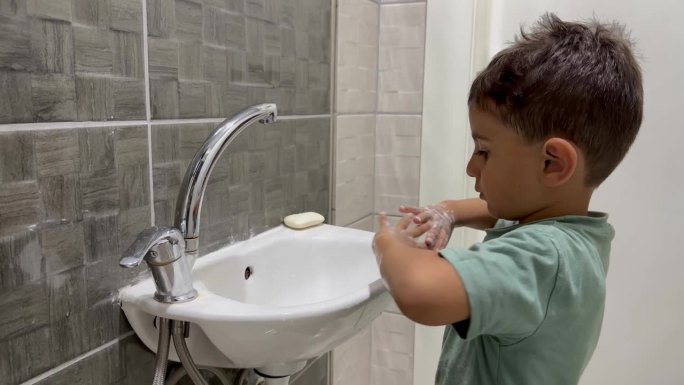 小男孩在水池里用肥皂洗手。
