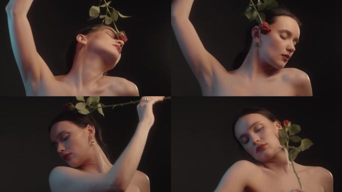 性感的女人用红色的口红和纹身黑色背景工作室拍摄跳舞与一个单一的红玫瑰和感觉花瓣对皮肤