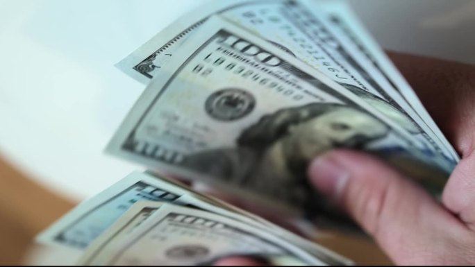 一名男子在白色背景上近距离叙述钱的手。许多一百美元的钞票。